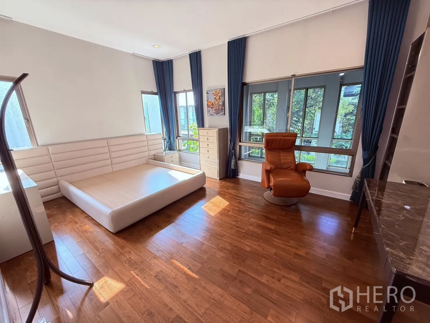 บ้านเดี่ยว for rent or sale in Prawet, Bangkok - ห้องนอนขนาดใหญ่พร้อมฐานเตียง เบาะเอนนั่ง หน้าต่างหลายบาน และพื้นไม้.