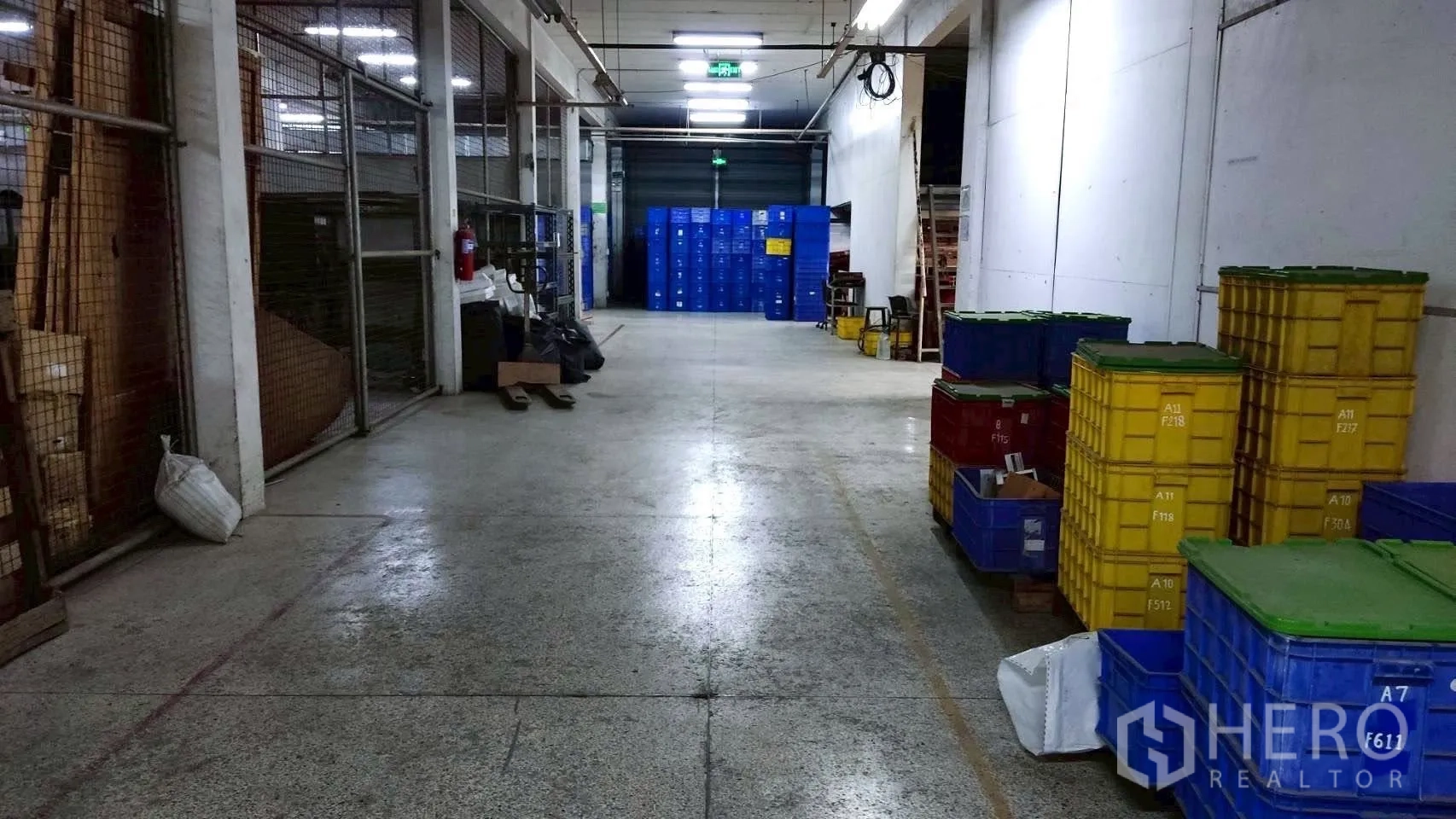 工厂 for sale in Lat Krabang, Bangkok - 储存通道，金属网围与成堆塑料箱，尽头为卷闸门。