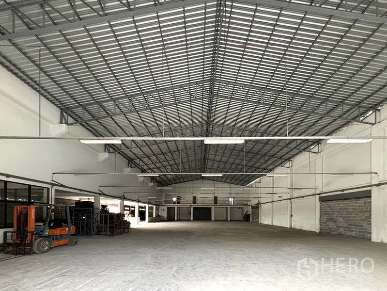 Warehouse for rent in Bang Khun Thian, Bangkok - Open-plan storage hall with high-span roof, bright lighting, and forklift area.