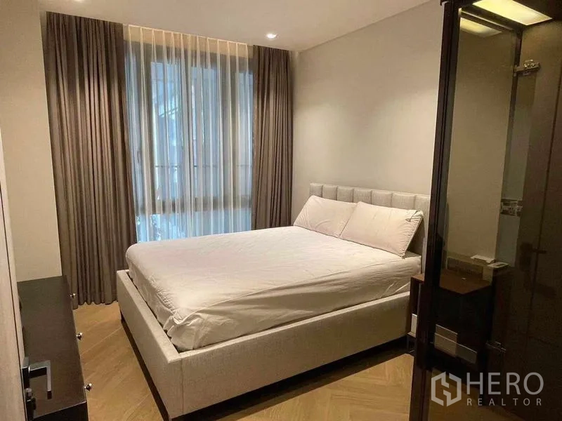 Condominium for rent - Second bedroom with double bed, layered curtains and warm wood flooring.