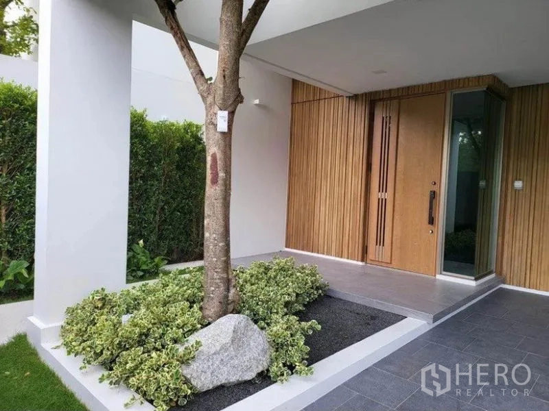 บ้าน ให้เช่าในSaphan Sung, Bangkok - ชานหน้าบ้านแบบมีหลังคา กรุไม้แนวตั้ง ประตูหน้าบ้านกระจก พร้อมสวนหย่อมต้นไม้และหินประดับ