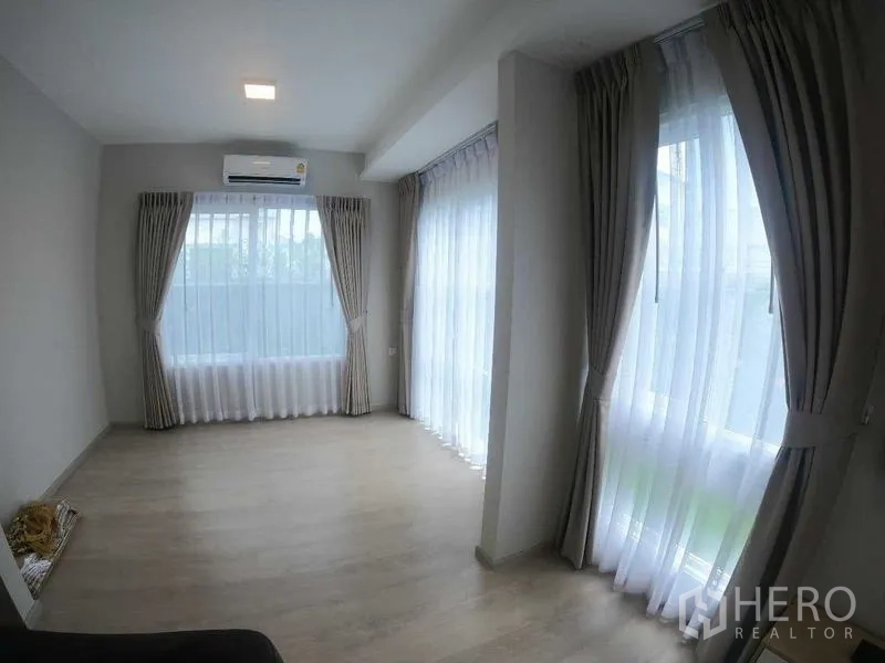 Townhouse for rent - Sunlit multipurpose area with wraparound windows and neutral curtains.