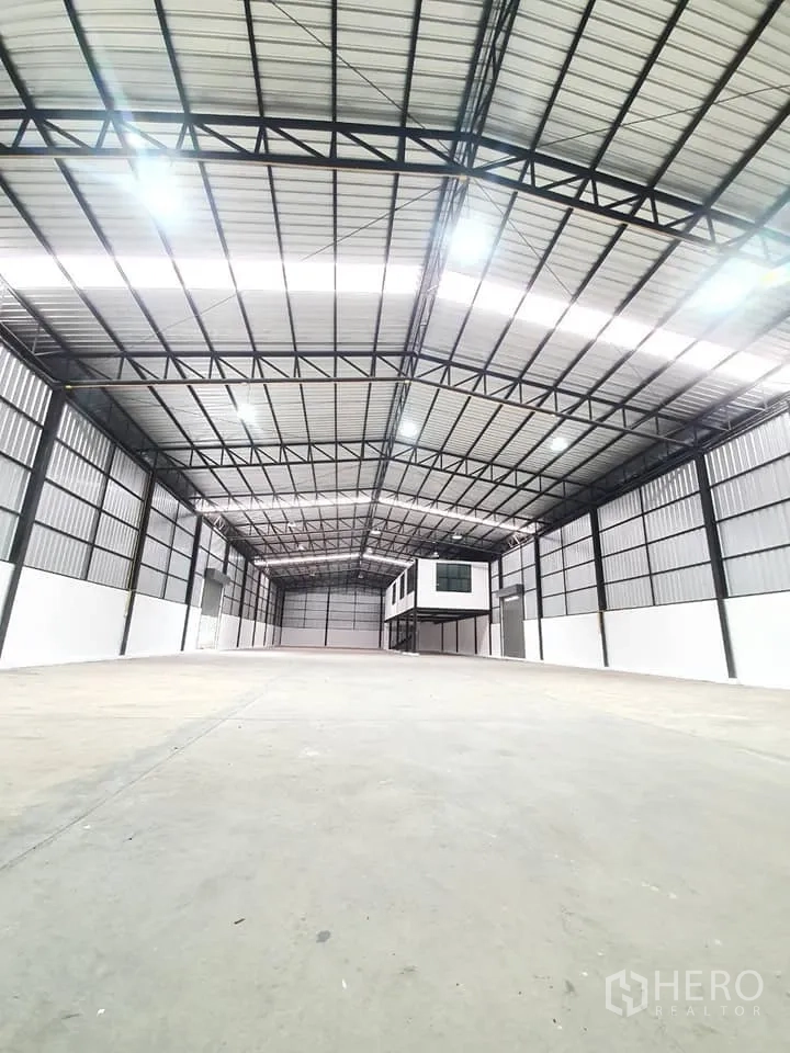 货栈 出租在Bang Khen, Bangkok - 开阔无柱库厅，灯光明亮，尽头设有架空盒式办公室。