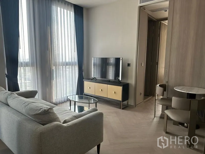 Condominium for rent - Bright living room with gray sofa, TV console and floor-to-ceiling windows in a Sathon condo.