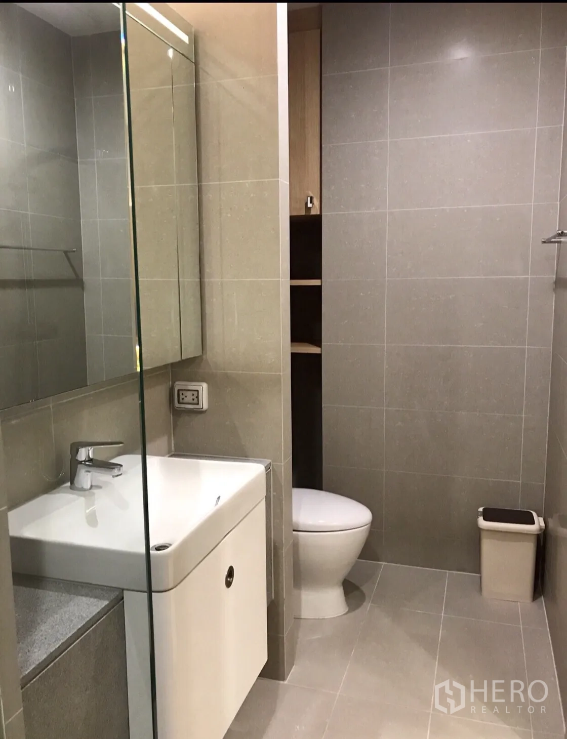 Condominium for rent in Pathum Wan, Bangkok - Contemporary bathroom with glass shower enclosure, tiled walls, vanity and toilet.