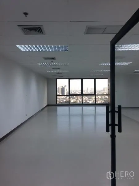 Office Space for rent in Bang Rak, Bangkok - Glass door opening to a bright open office floor with wide windows, grid ceiling lights and skyline outlook.