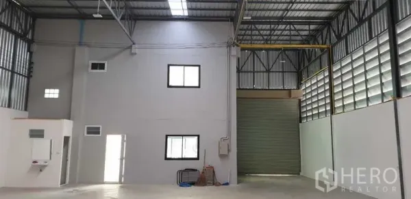 Factory for rent in Lam Luk Ka, Pathum Thani - High-ceiling warehouse interior with steel trusses, internal office block and wide roller shutter door.