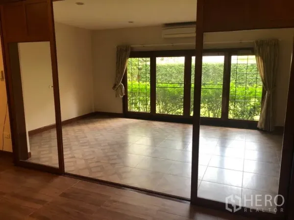 Detached House for rent in Watthana, Bangkok - Sunlit room with large windows and views to a green garden hedge.