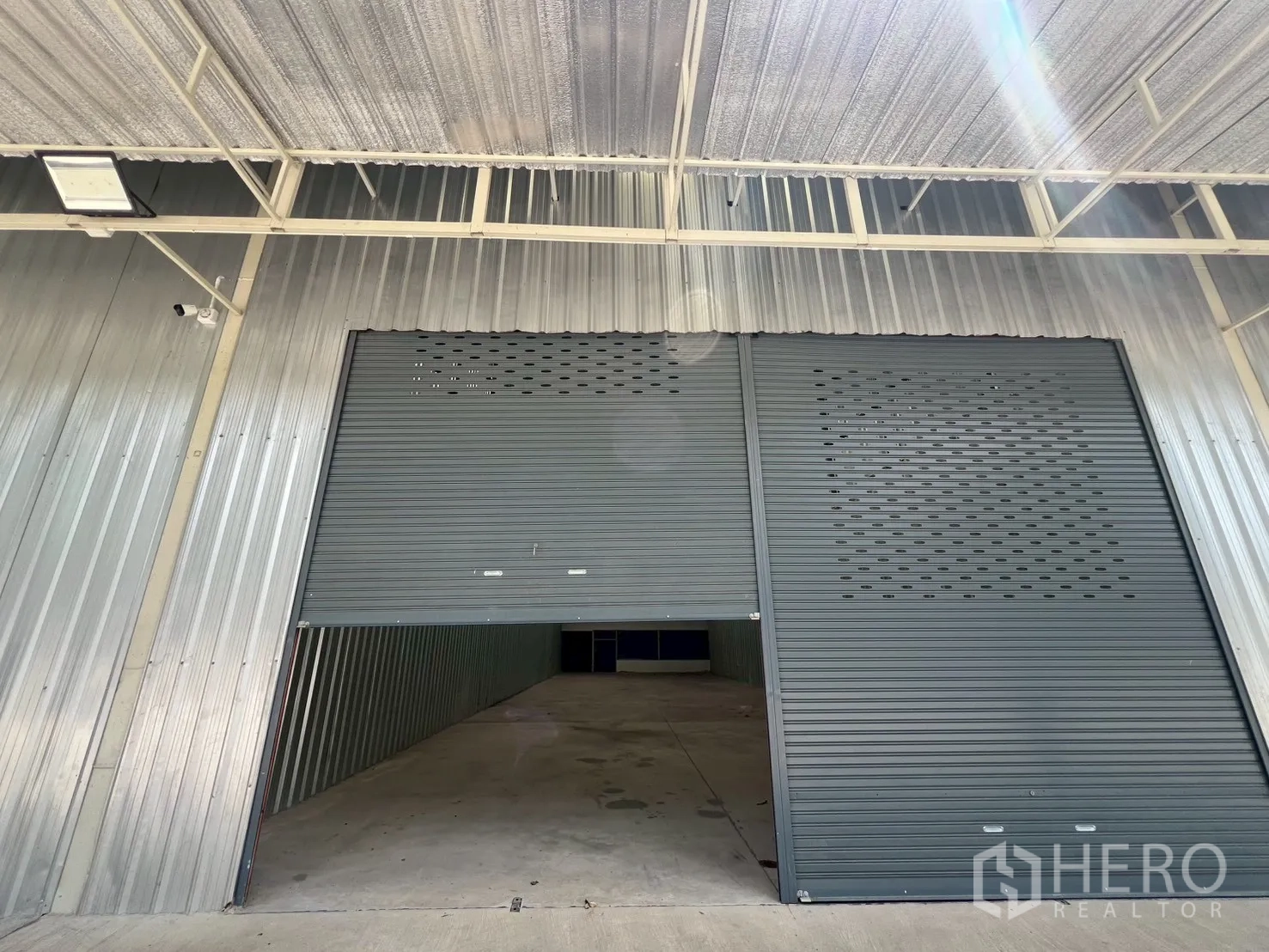 คลังสินค้า ให้เช่าในMin Buri, Bangkok - มุมใกล้ทางเข้าโกดัง ประตูม้วนเปิดบางส่วน ใต้กันสาดสำหรับขนส่ง