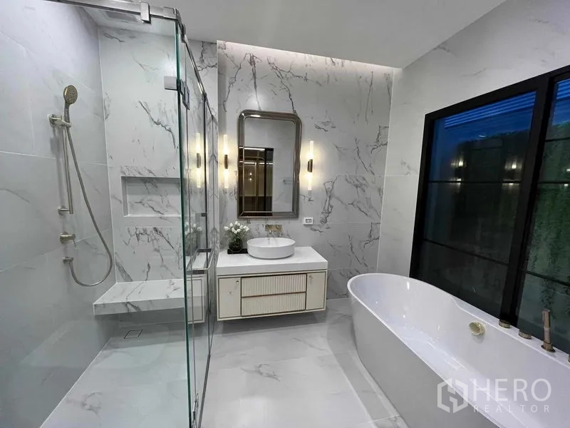 Detached House for rent in Saphan Sung, Bangkok - Luxury bathroom with freestanding bathtub, glass-enclosed shower, marble walls and vanity.