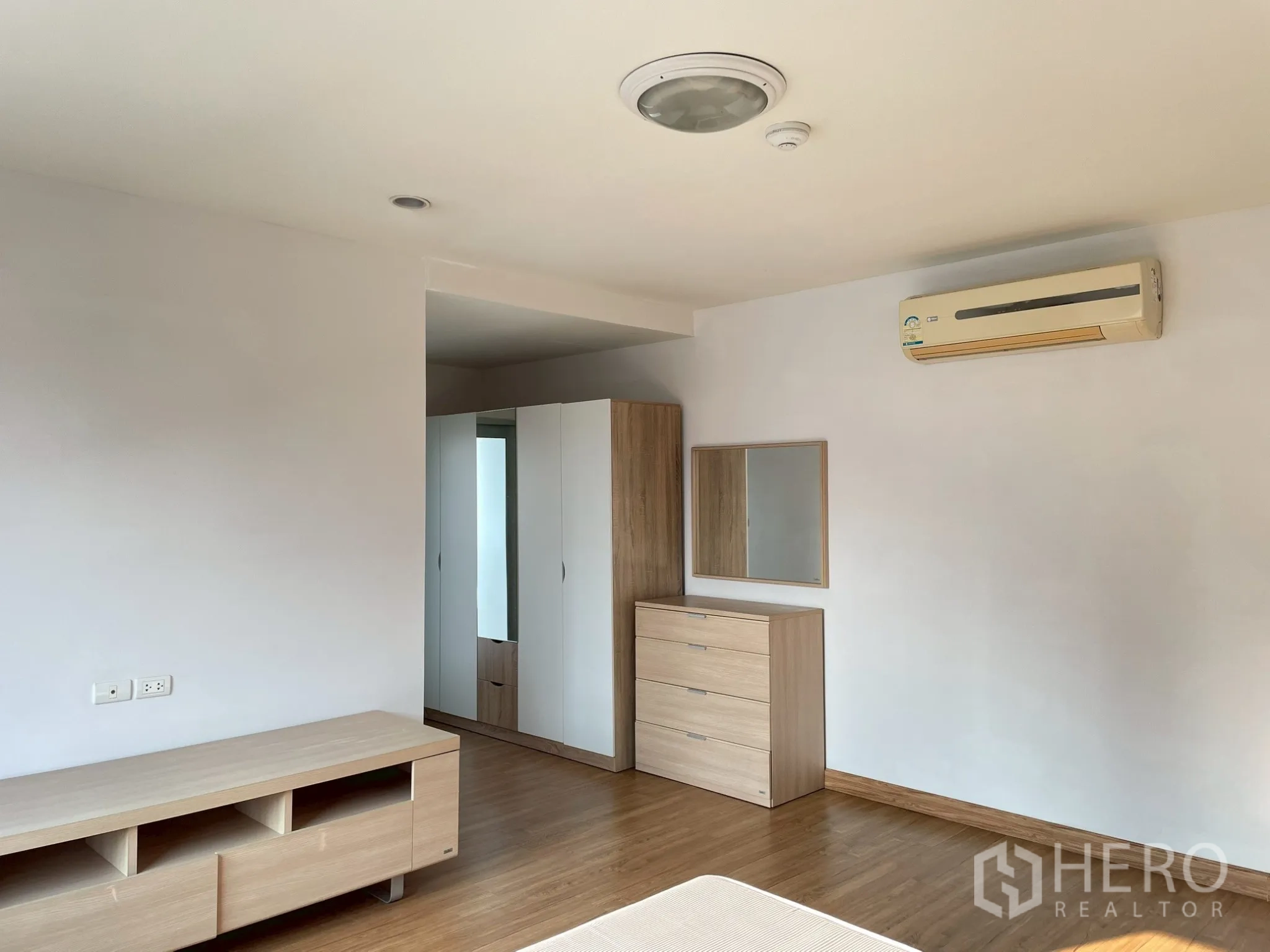 Apartment for rent in Khlong Toei, Bangkok - Bedroom with air conditioner, dresser, and TV cabinet.