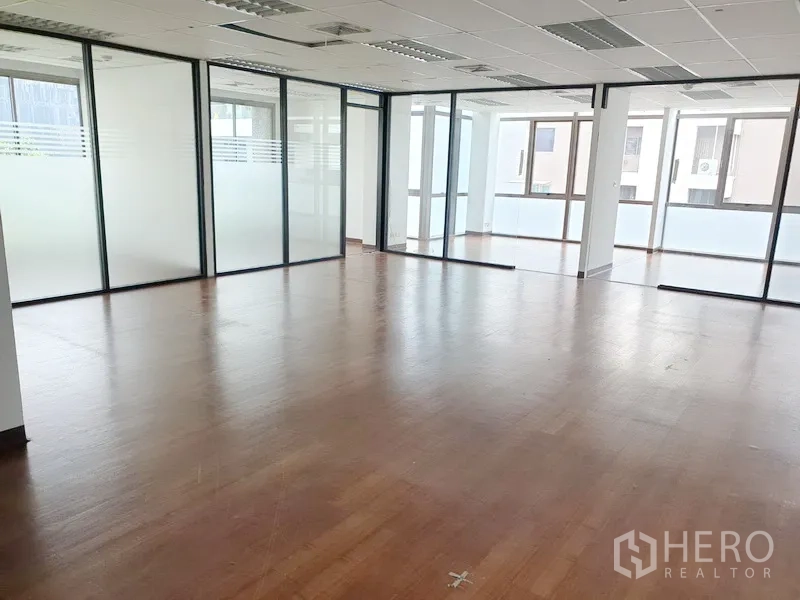Office Space for rent in Khlong Toei, Bangkok - Bright open-plan office with wood flooring, drop ceiling, and glass-partitioned rooms with large windows.
