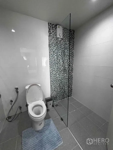 Condominium for rent in Watthana, Bangkok - Bathroom with glass shower partition and mosaic-tile accent wall.