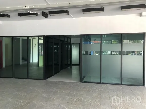 零售空间 出租在Wang Thonglang, Bangkok - 店内入口，落地玻璃隔断带磨砂条纹，地砖与天花照明清晰可见。