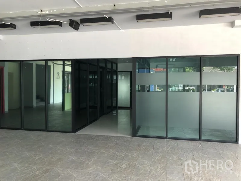 零售空间 出租在Wang Thonglang, Bangkok - 店内入口，落地玻璃隔断带磨砂条纹，地砖与天花照明清晰可见。