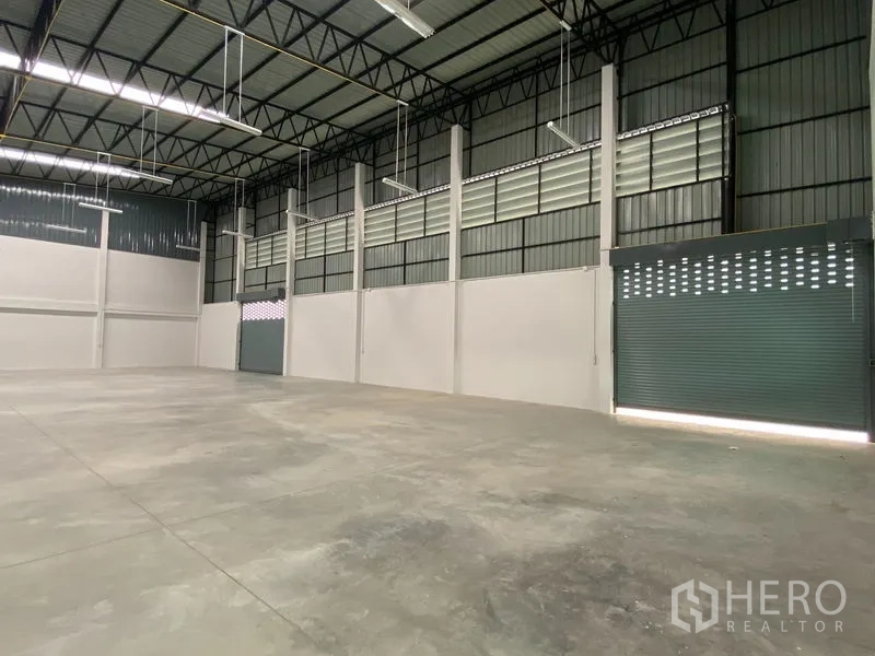 Warehouse for rent or sale in Bang Len, Nakhon Pathom - Spacious warehouse interior with high ceilings, steel trusses and roller doors.