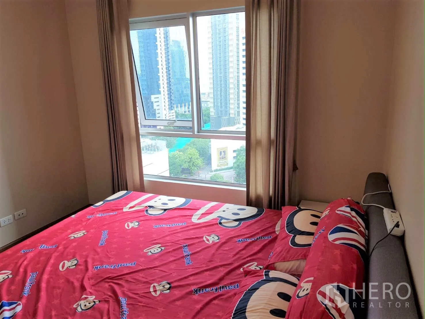 Condominium for rent in Huai Khwang, Bangkok - Bright bedroom with large window, curtains, and a clear city skyline view.
