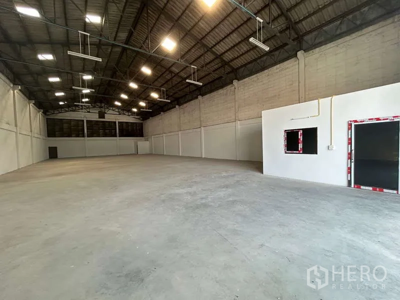Warehouse for rent in Khlong Toei, Bangkok - Spacious warehouse interior with high steel truss ceiling, bright lights, concrete floor and small office room.