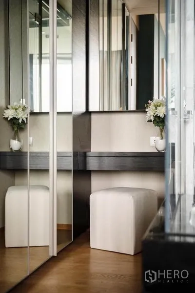 公寓 出租或出售在Bang Rak, Bangkok - 更衣区，镜面衣柜、梳妆台与白色方形坐凳。