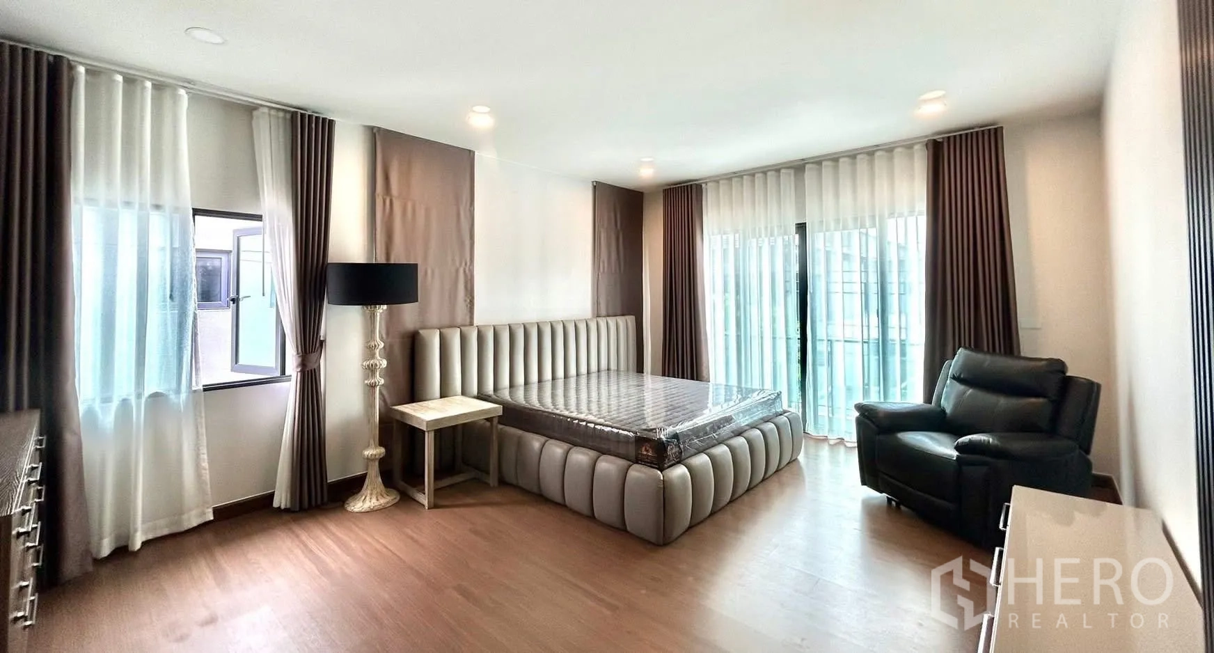 独栋房屋 for rent in Bang Phli, Samut Prakan - 宽敞主卧，软包大床、躺椅和通向阳台的落地门。