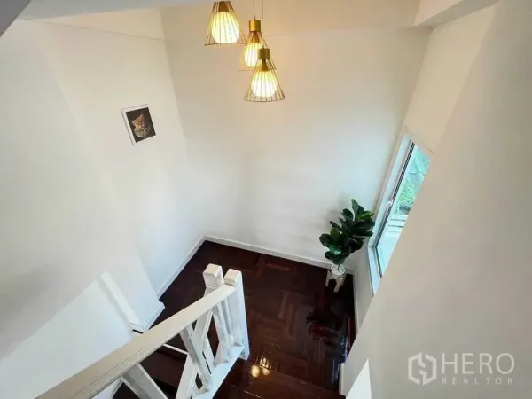Detached House for sale in Bang Bon, Bangkok - Bright stairwell with white railing, pendant lights and a window over glossy wood flooring.