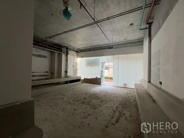 Retail Space for rent in Khlong Toei, Bangkok - Deep retail floor plate with unfinished concrete floors and daylight from the glass door.