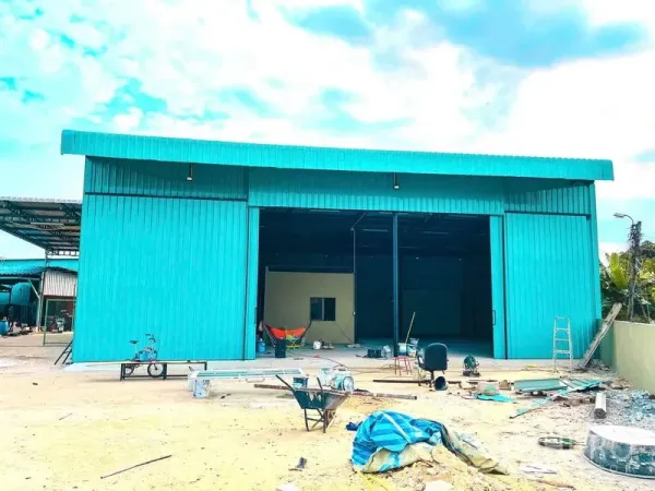 Warehouse for rent in Sai Mai, Bangkok - Front exterior of teal metal-clad warehouse with large sliding doors and open forecourt.