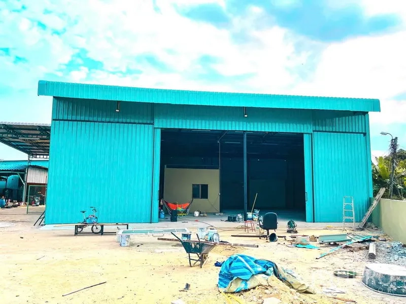 Warehouse for rent in Sai Mai, Bangkok - Front exterior of teal metal-clad warehouse with large sliding doors and open forecourt.