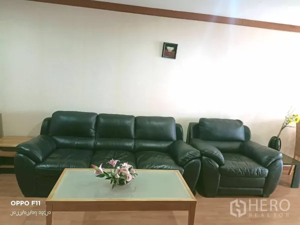 คอนโด ให้เช่าในKhlong Toei, Bangkok - โซฟาหนังพร้อมโต๊ะกลางกระจกในห้องนั่งเล่นโทนอบอุ่น