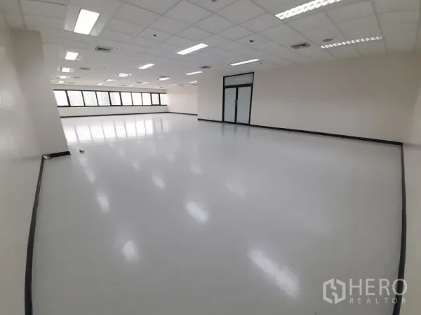 办公空间 出租在Bang Rak, Bangkok - 开放式办公空间，亮面地坪、整排窗户和玻璃门，格栅天花灯光。