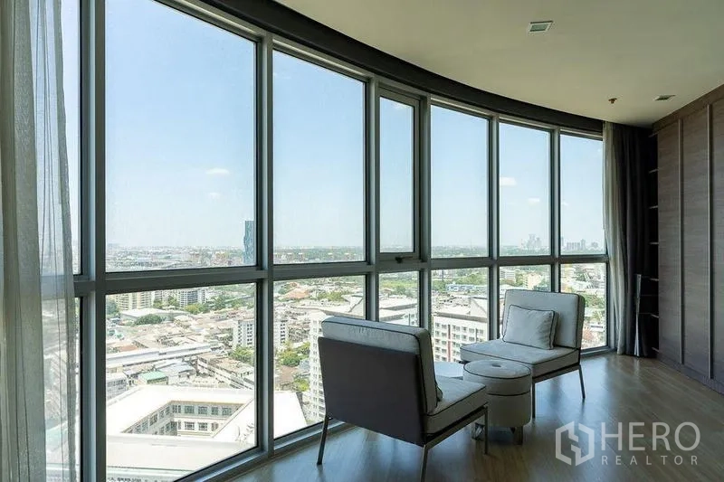 Condominium for rent - Corner glass bay with two armchairs showcasing a wide city panorama.