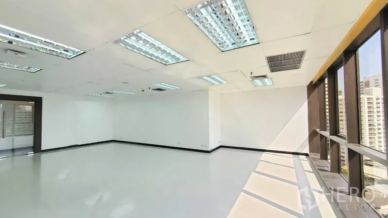 Office Space for rent in Watthana, Bangkok - Corner office zone with full-length windows, glossy floors, and a glass entry door letting in natural light.