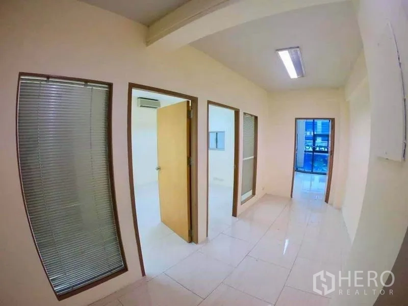 Office Space for rent in Khlong Toei, Bangkok - Corridor with partitioned private offices, glass panels with blinds and white tiles.