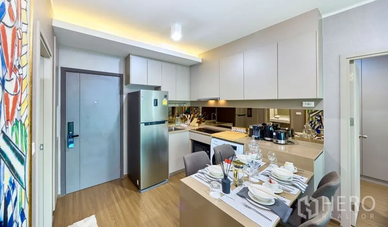 Condominium for rent in Phra Khanong, Bangkok - Fully fitted kitchenette with mirrored backsplash, ample cabinetry and a set dining table.