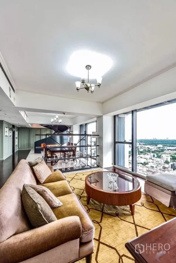Condominium for rent in Sathon, Bangkok - Upper living area with sofa and round coffee table facing city views beside a sculptural spiral staircase.