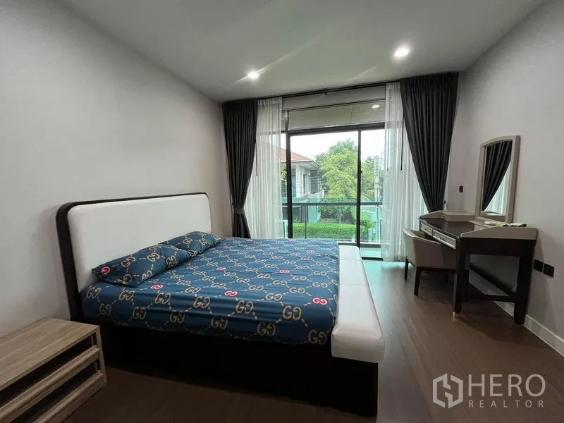 Detached House for rent in Bang Kapi, Bangkok - Master bedroom with bed, vanity and balcony access overlooking greenery