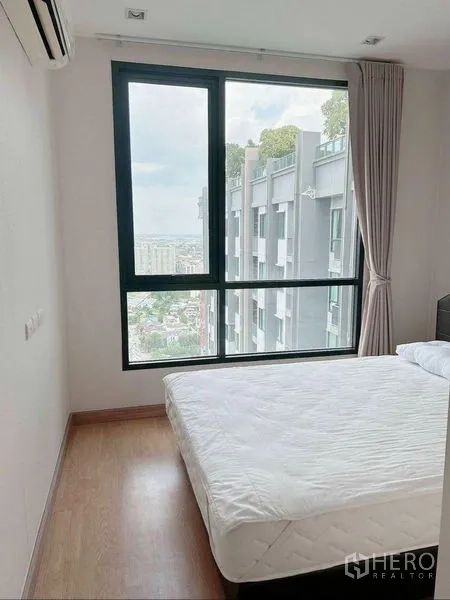 Condominium for rent in Watthana, Bangkok - Bedroom with large window and sweeping city view near BTS On Nut.