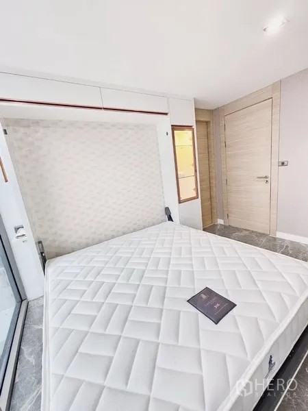 Condominium for sale in Bang Rak, Bangkok - Murphy bed folding down in a bright room next to floor-to-ceiling window.