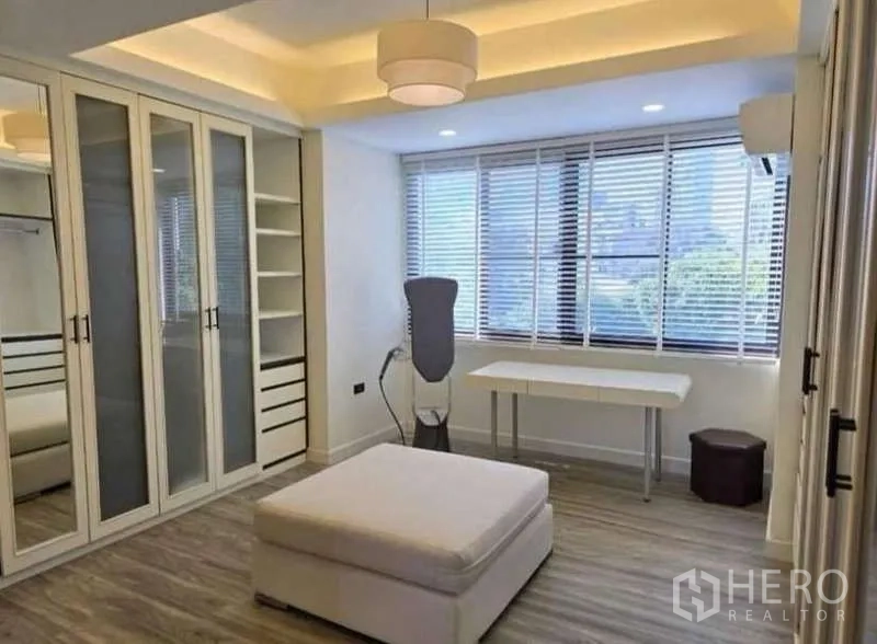 Townhouse for rent - Sunlit bedroom or dressing room with built-in wardrobes, desk, and ottoman.