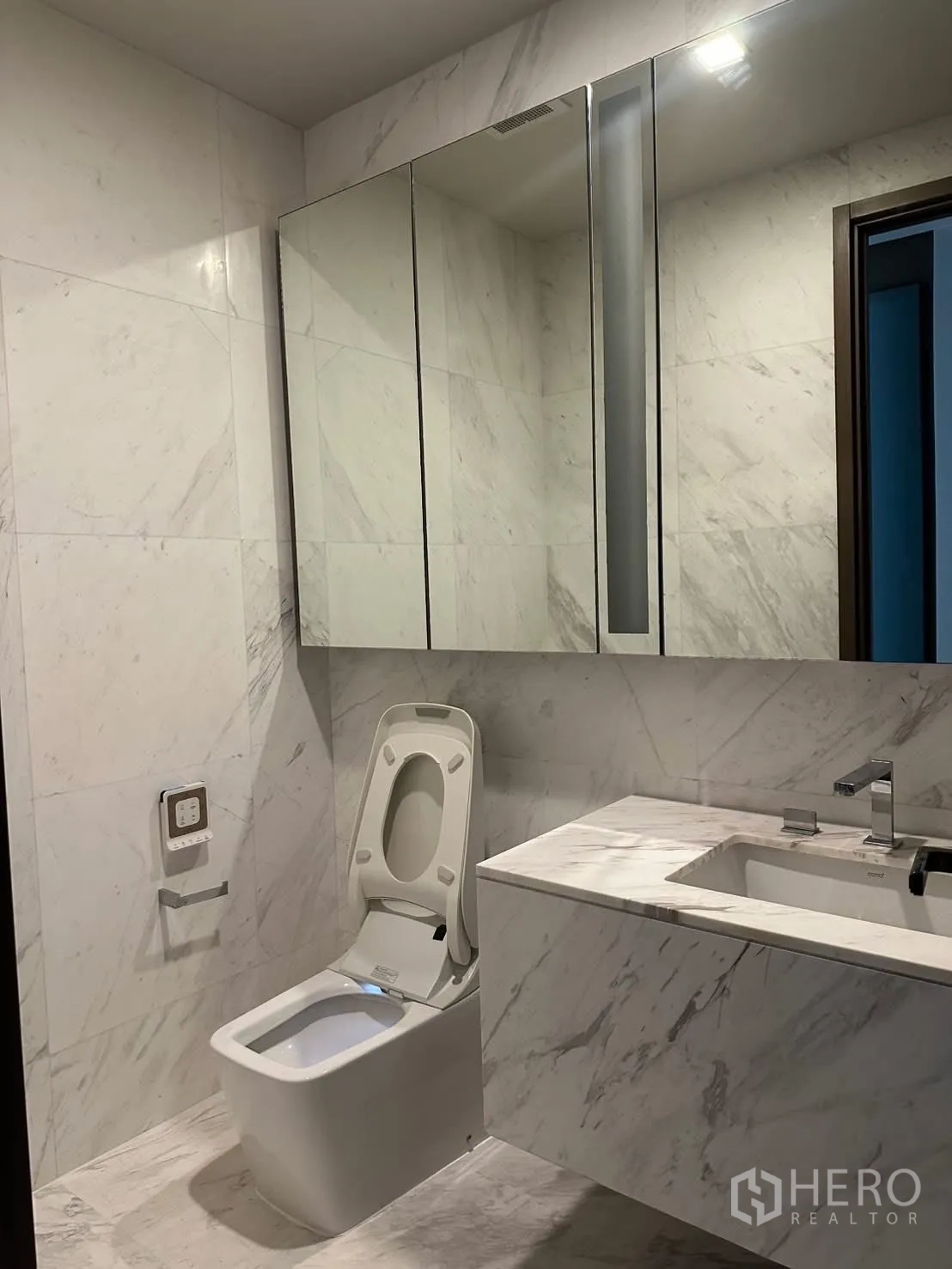 Condominium for rent or sale in Watthana, Bangkok - Light marble bathroom with mirrored cabinets and smart toilet.