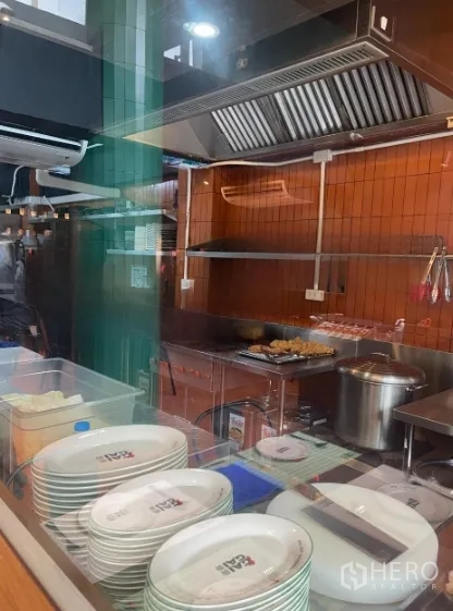 店屋 出租在Watthana, Bangkok - 玻璃后方的开放式厨房，配不锈钢排烟罩与烹饪设备。