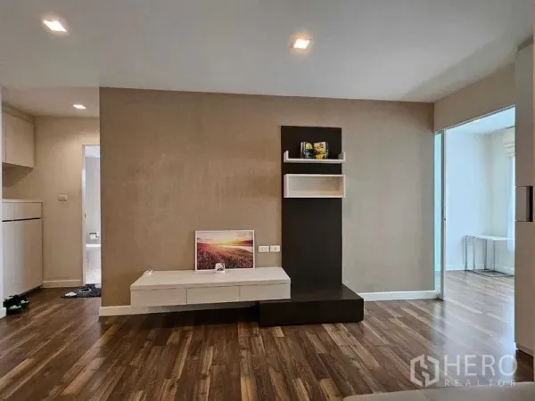 Condominium for sale in Watthana, Bangkok - Feature wall with built-in TV console and shelves in the open-plan living space.