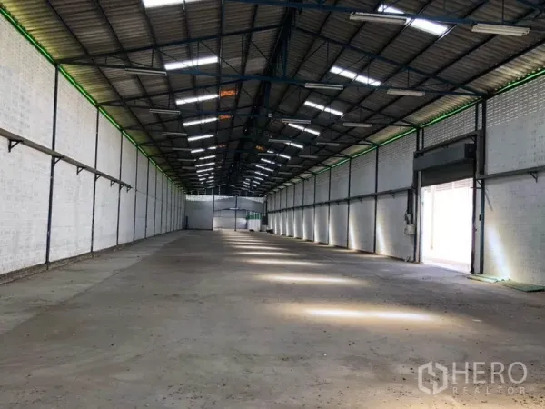 工厂 出租在Nonthaburi - 仓库内部带卷帘装卸门，天窗采光充足，空间开阔无柱。