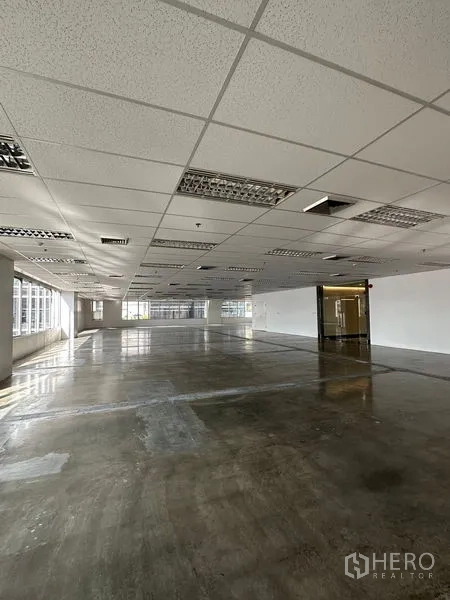 办公空间 出租在Pathum Wan, Bangkok - 开放式办公室楼层，玻璃入口、荧光照明、吊顶出风口与大面积转角窗。