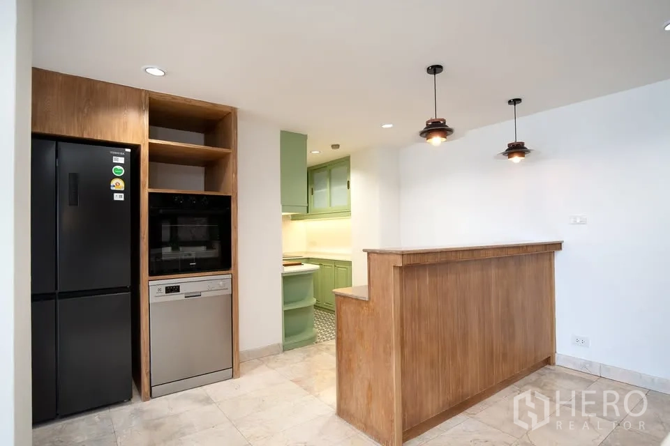 公寓 for rent in Watthana, Bangkok - 开放式厨房，木吧台、吊灯与绿色橱柜。