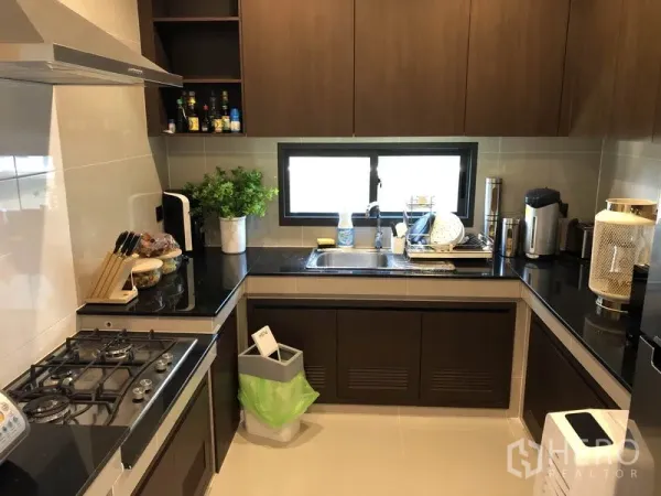 Detached House for rent in Bang Kapi, Bangkok - Separate Thai kitchen with gas hob, hood, black countertops and abundant cabinetry.