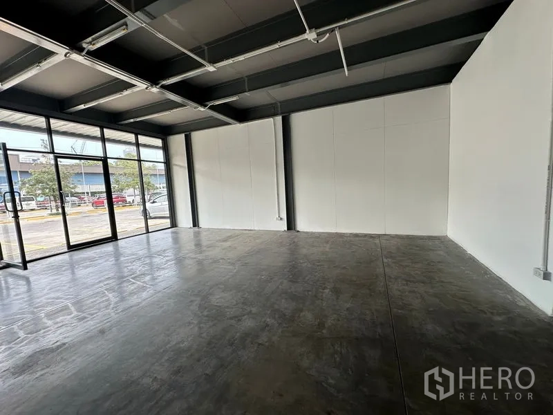 Office Space for rent in Khlong Toei, Bangkok - Open-plan office with polished concrete floor, exposed beams and full-height glass frontage facing parking.