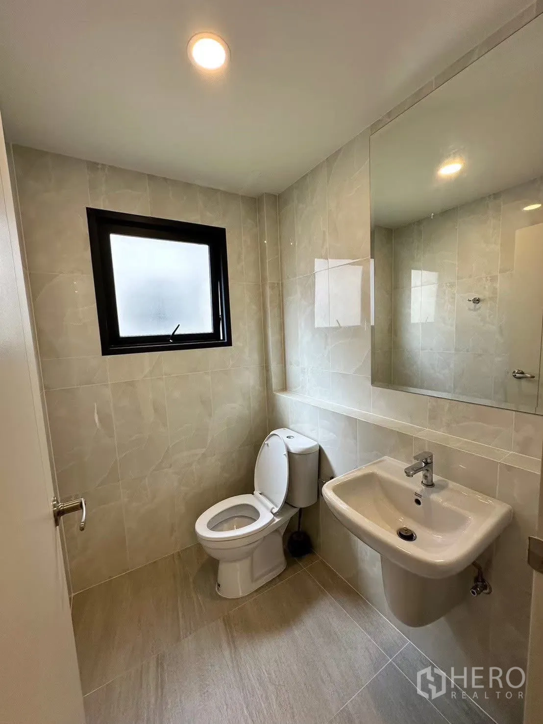 Detached House for rent in Bang Phli, Samut Prakan - Guest bathroom finished in beige tiles with window, toilet and sink.