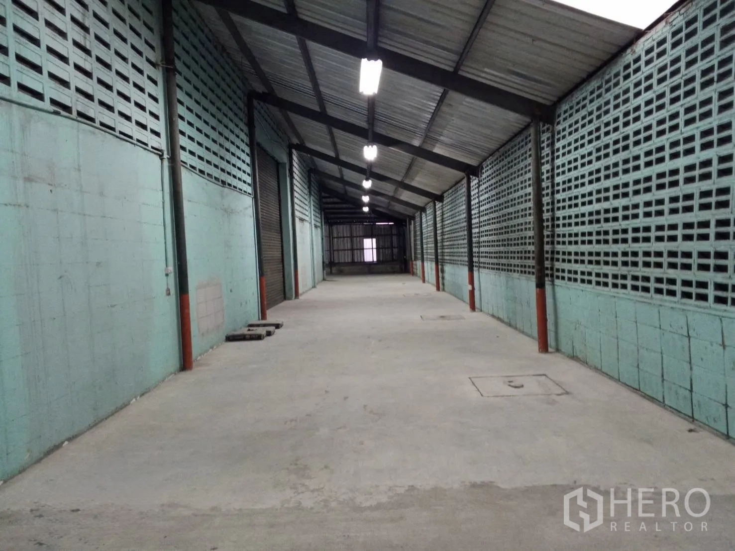 Warehouse for rent in Min Buri, Bangkok - Covered side bay with ventilation block walls, concrete floor and linear lighting.