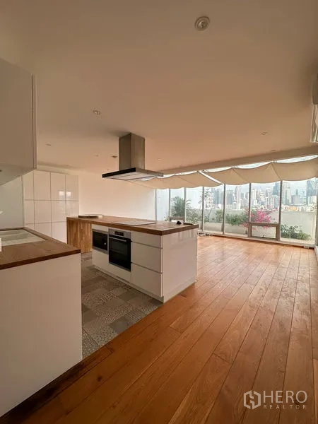 คอนโด ให้เช่าในKhlong Toei, Bangkok - ครัวและพื้นที่นั่งเล่นหันสู่ระเบียงพร้อมวิวเมืองพาโนรามาและกระถางต้นไม้